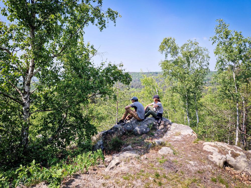 stage de survie - deux personne sur un rocher dans la foret, il fait jour 